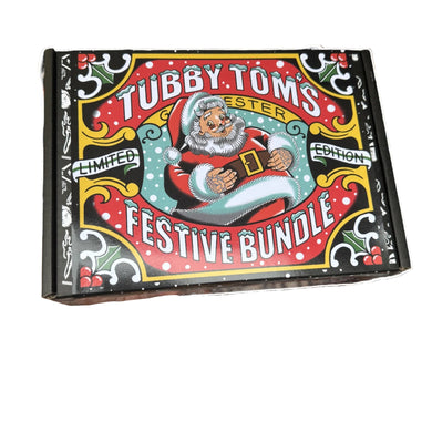 Tubby Toms Festive Bundle box held in front of a fireplace with Christmas decorations.