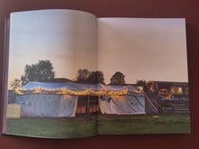 Load image into Gallery viewer, Open book showing a photograph of tents and a food truck at dusk.