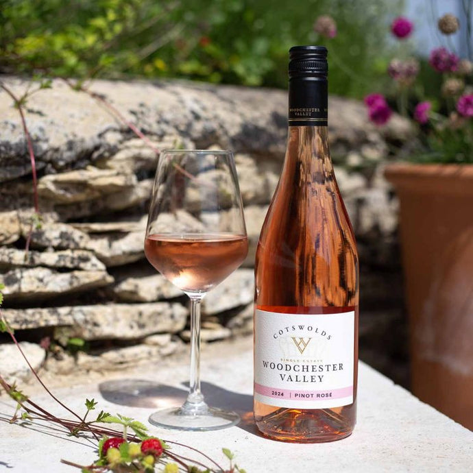 Bottle and glass of Woodchester Valley rosé wine with a garden background
